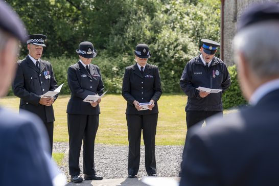 Police representatives bow their heads as prayers are spoken at the Memorial service