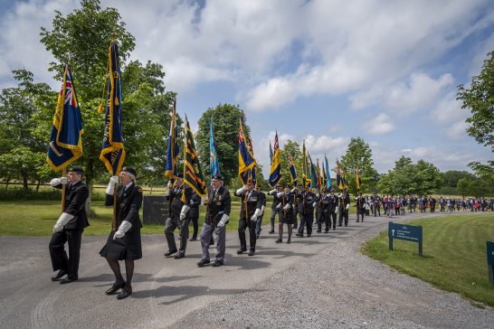 Standards are proudly paraded by veterans in the memorial procession.