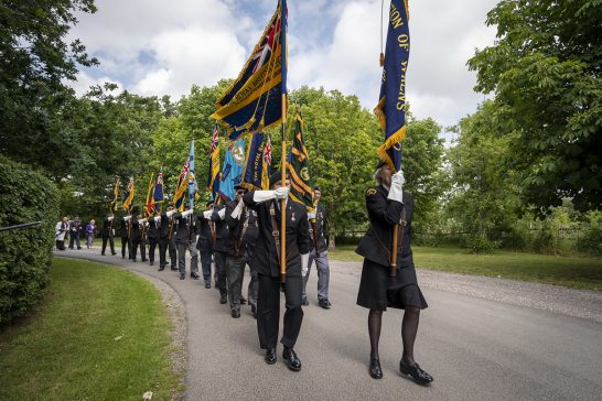 Standards are proudly paraded by veterans in the memorial procession to the Memorial stone..