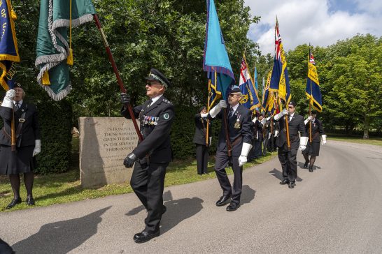 The parade moves through the Memorial Woodlands, led by military representatives.